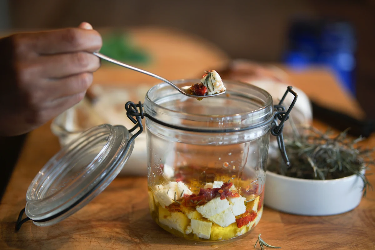 Bocal hermétique avec feta immergée dans huile d'olive et herbes pour conservation optimale